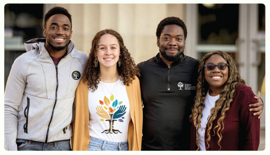 Photo of 4 diverse, young camp counselors outside a community center